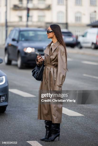 Nephtys Laurent wears brown varnished coat, black bag, boots outside OpéraSport during the Copenhagen Fashion Week Autumn/Winter 2023 on February 01,...