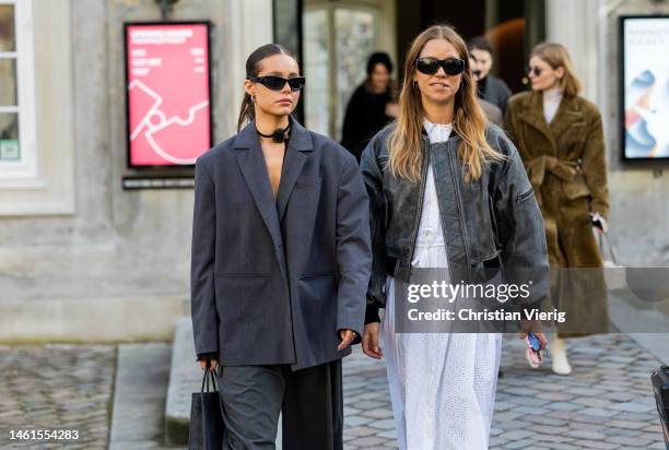 Trine Kjaer wears bomber leather jacket in grey, white dress and a guest wears oversized grey blazer, pants outside Skall Studio during the...