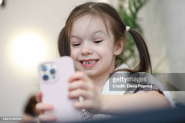 beautiful 6 years old girl talking by phone and showing her lost primary tooth - tooth fairy stock pictures, royalty-free photos & images
