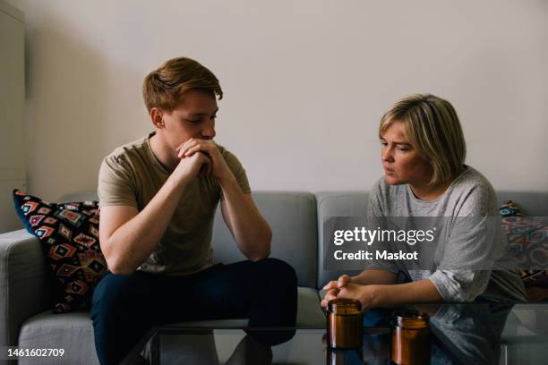parent consoling man while sitting on sofa at home - boomerang generation stock pictures, royalty-free photos & images