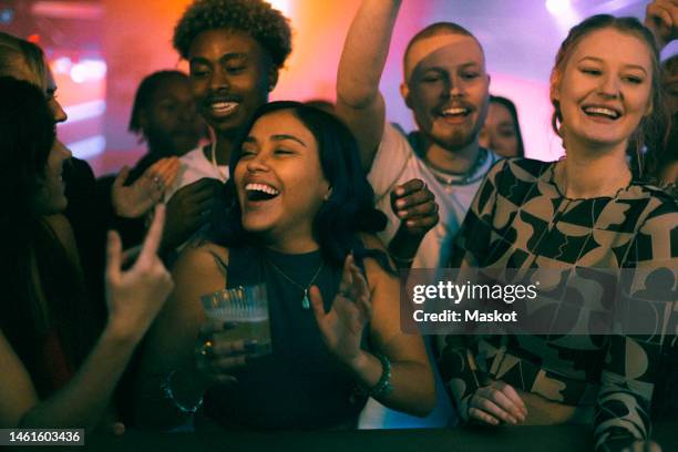 cheerful female and male friends dancing while celebrating weekend party in club - feest stockfoto's en -beelden