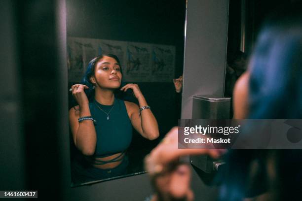 reflection of young woman looking at mirror reflection in nightclub bathroom - beautiful people party stock pictures, royalty-free photos & images