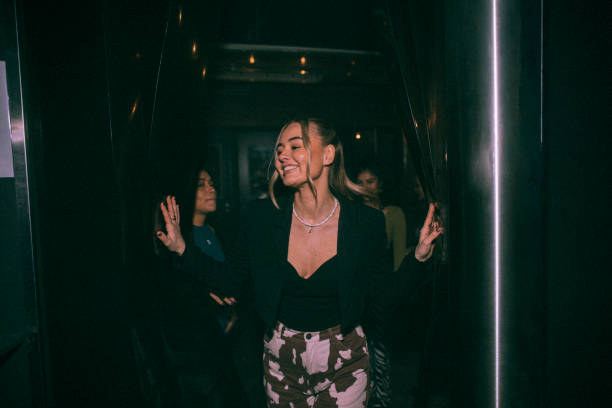  cheerful young woman getting out of bathroom with friends in background at nightclub - night club stock pictures, royalty-free photos & images
