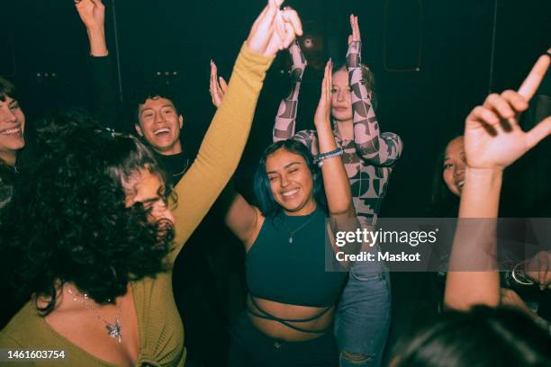 cheerful young friends dancing and enjoying together at nightclub - nightclub fotografías e imágenes de stock