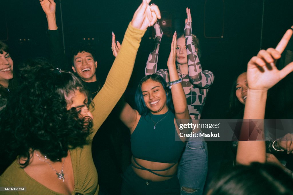 Cheerful young friends dancing and enjoying together at nightclub
