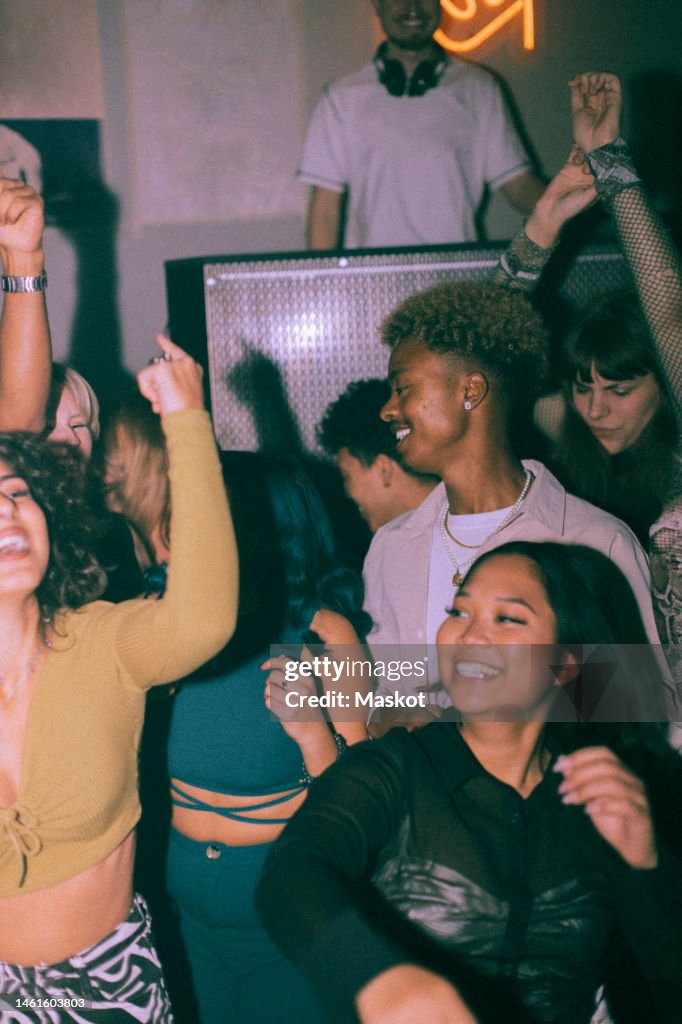 Cheerful young multiracial men and women dancing at nightclub