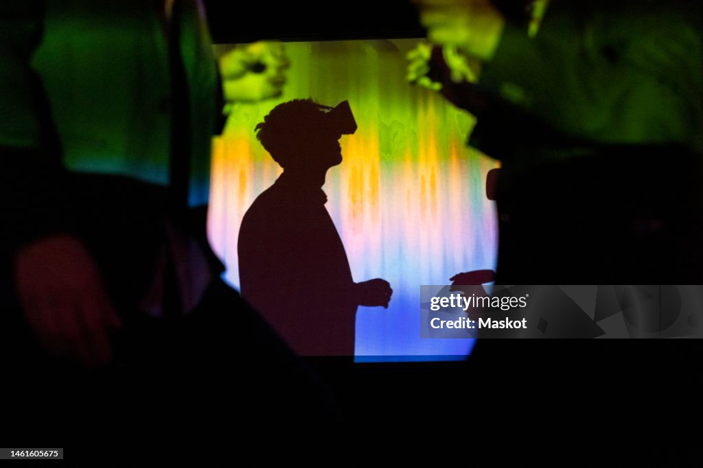 Side view of businessman watching through virtual reality glasses in exhibition center