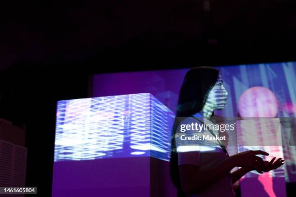 side view of businesswoman gesturing by projection screen in illuminated convention center - beamern stock-fotos und bilder