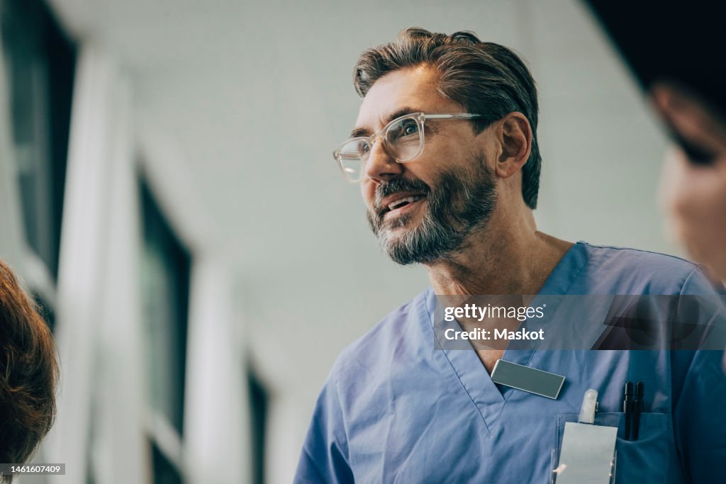 Low angle view of smiling mature male doctor wearing eyeglasses at hospital