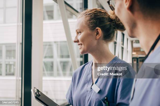 smiling female nurse looking through window at hospital - nurse headshot stock pictures, royalty-free photos & images