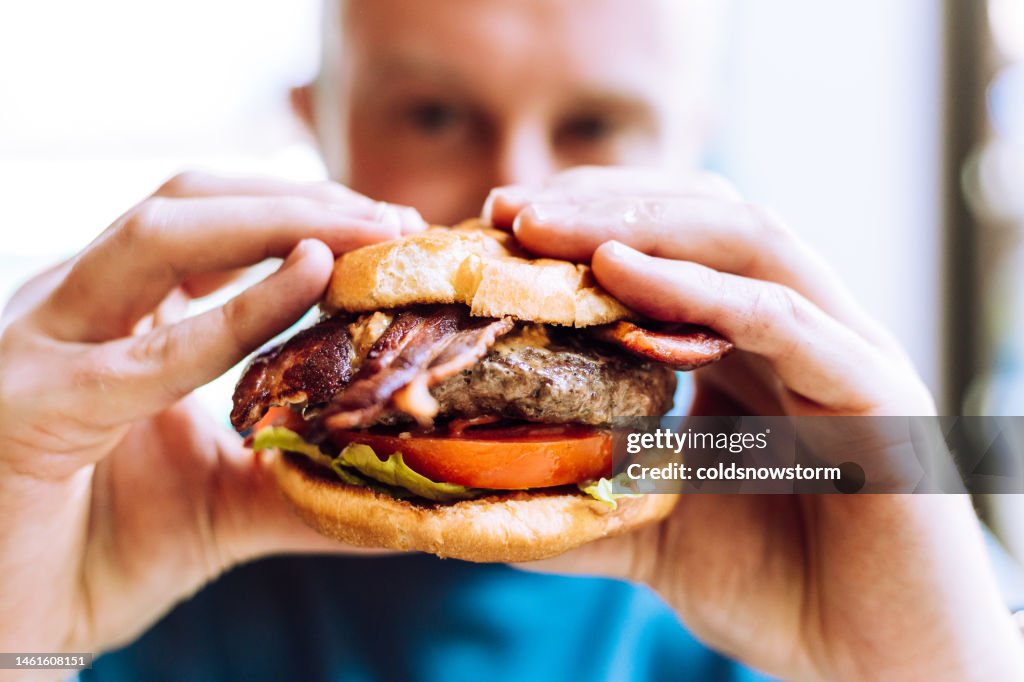 Man holding delicious fresh flame grilled burger in restaurant