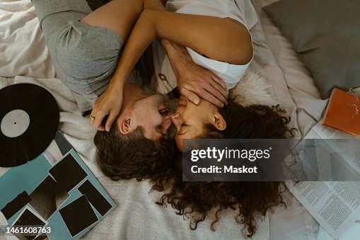 Directly above view of romantic couple rubbing noses while lying on bed at home Directly above view of romantic couple rubbing noses while lying on bed at home