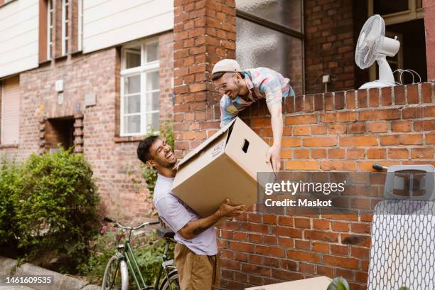 happy gay couple helping each other during relocation of house - gay couple new house stock pictures, royalty-free photos & images