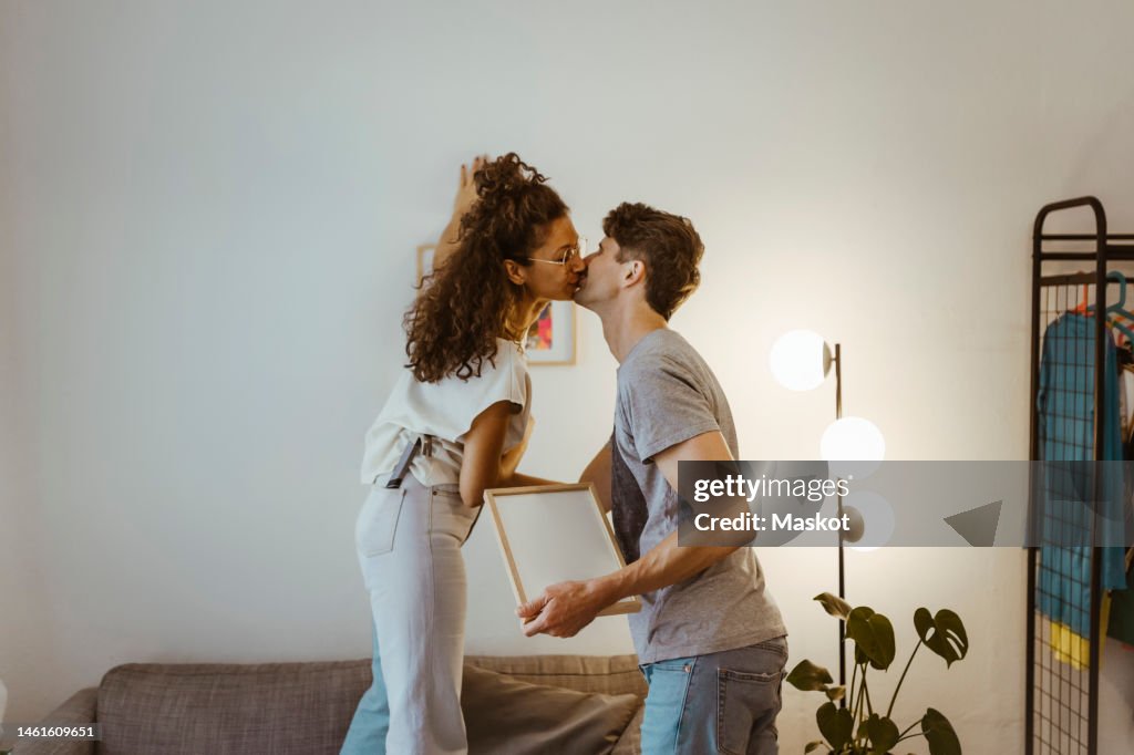 Side view of couple kissing each other against wall at home