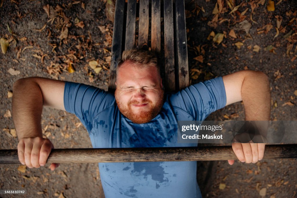 Directly above shot of determined obese man doing bench press at park