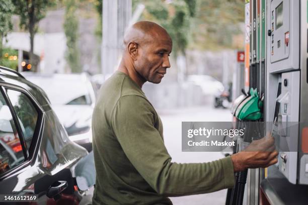 side view of mature man doing payment through credit card while standing at gas station - auto garage stock pictures, royalty-free photos & images