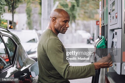Side view of mature man doing payment through credit card while standing at gas station Side view of mature man doing payment through credit card while standing at gas station