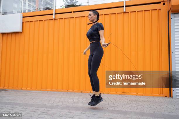 pretty young woman skipping rope in the industrial setting - jump rope stockfoto's en -beelden