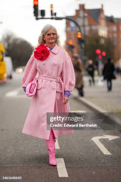 Guest wears orange and rhinestones large sunglasses, a purple glitter high neck t-shirt, a pale pink and white tweed belted long coat with a large...