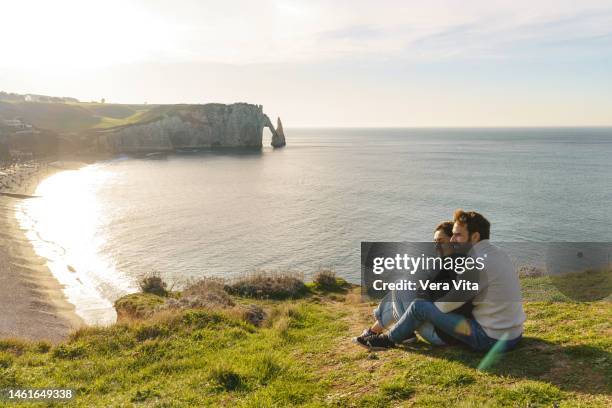 top panoramic view of caucasian young couple in love sightseeing at etretat cliff landscape at sunset - pareja de mediana edad fotografías e imágenes de stock