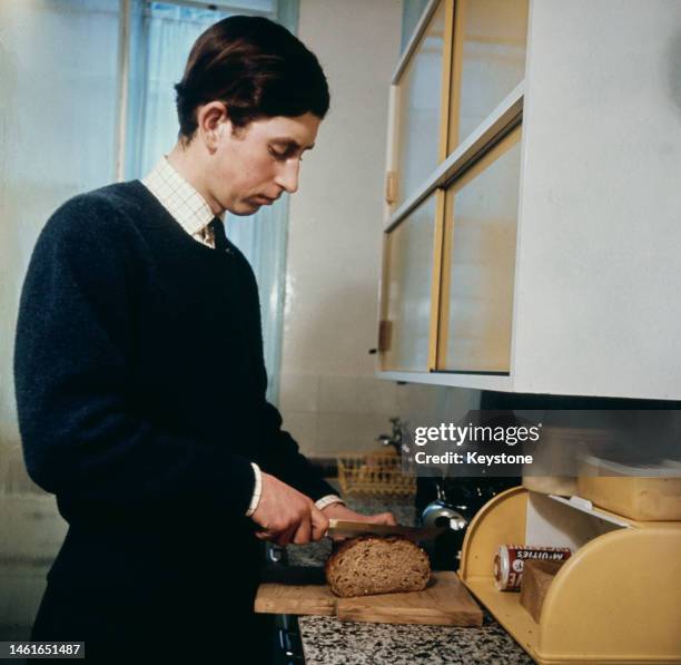Prince Charles cutting a slice of bread in his rooms at Cambridge University in 1969.