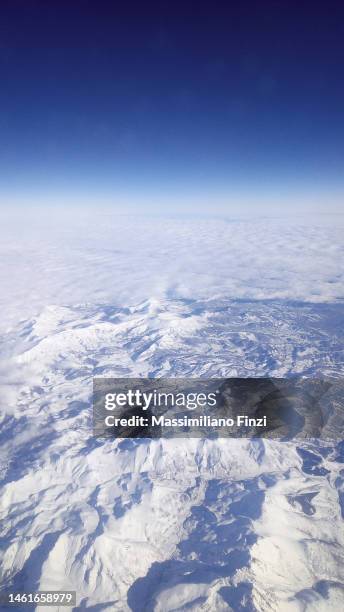 high angle view of the earth with the snowy mountains and the dark sky and the clouds above - 巻積雲 ストックフォトと画像