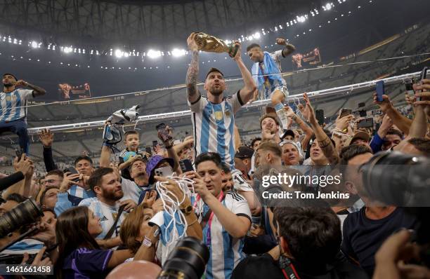 Lionel Messi of Argentina shows off the FIFA World Cup Trophy to fans while he is carried around the pitch on the shoulders of former teammate Sergio...