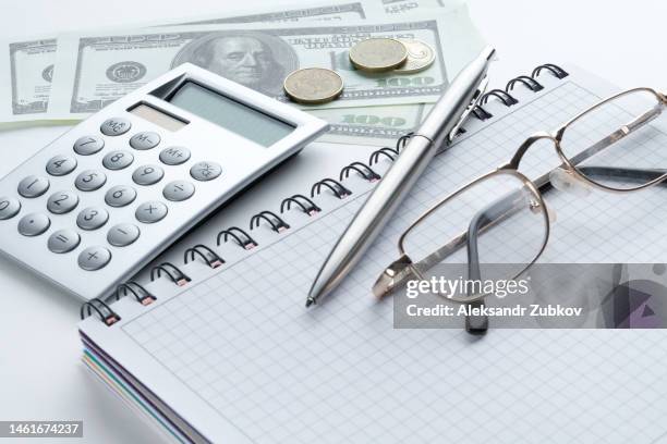 a calculator, a pen, glasses, an open notebook, and dollar bills lie on a white table. the concept of financial accounting of business entities, calculating business profits or losses, maintaining expenses and income. - accounting background stock pictures, royalty-free photos & images