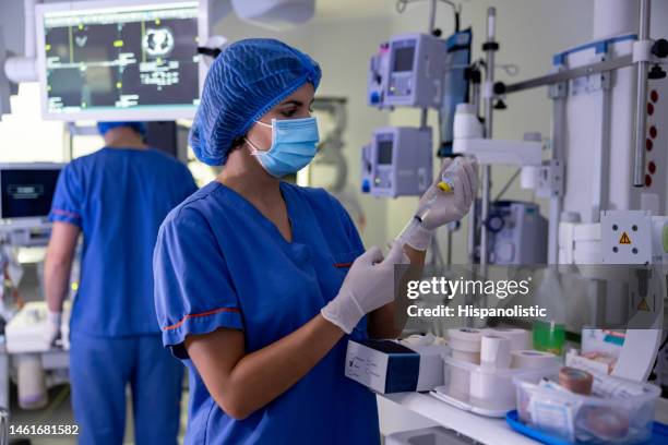 surgical nurse filling a syringe in the operating room - medical instrument stock pictures, royalty-free photos & images