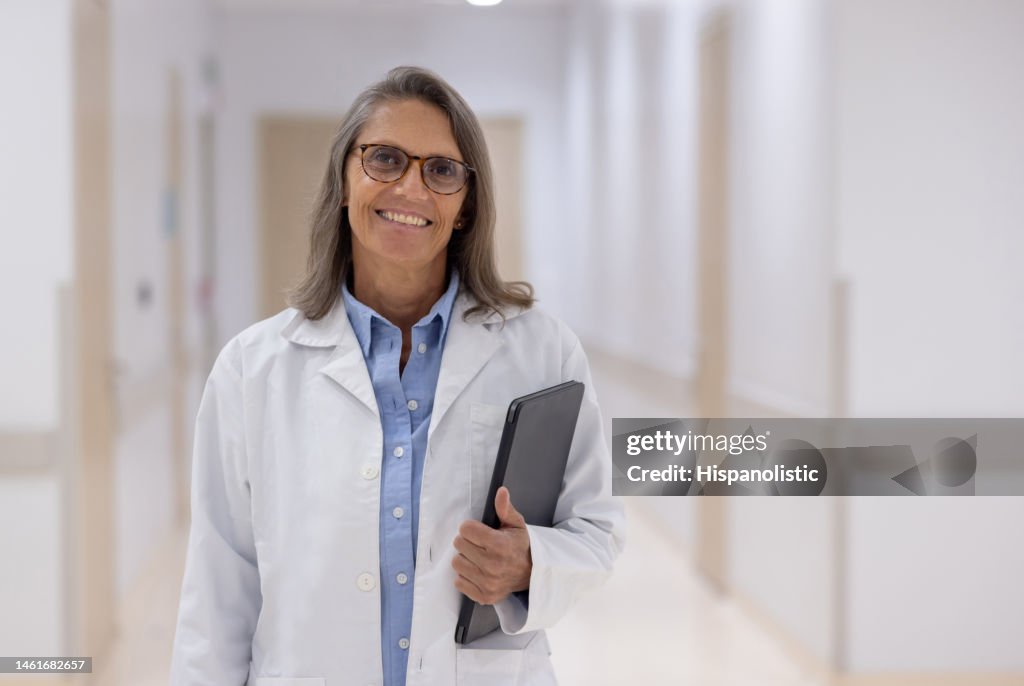 Happy doctor holding a tablet computer while working at the hospital
