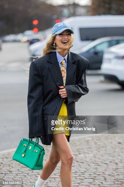 Emili Sindlev wears green Hermes bag, white socks, Adidas sneakers, black white striped blazer, tie with floral print, yellow skirt, blue button...