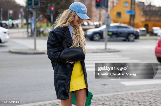 Emili Sindlev wears green Hermes bag, white socks, Adidas sneakers, black white striped blazer, tie with floral print, yellow skirt, blue button...