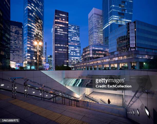 woman in silhouette using a public underpass at modern business distrct - woman capturing city night foto e immagini stock