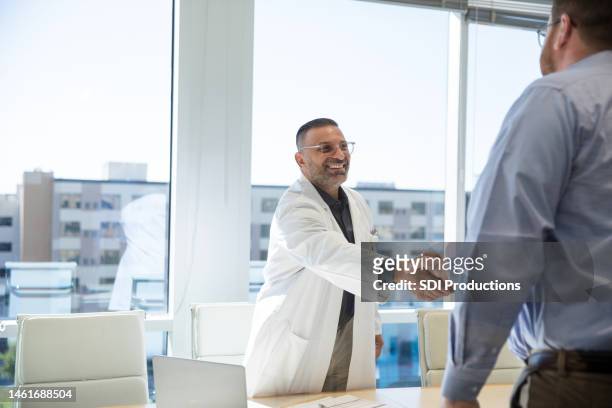 male hospital chief of staff greets unrecognizable male job applicant - arabic doctor stockfoto's en -beelden