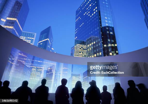 illuminated skyline of modern business district with people in silhouette looking at outdoor cinema - skyscraper film stock-fotos und bilder