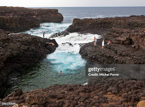 Cliff divers go into the water near Buracona also called Blue Eye, one of the main attractions, in the area on May 15, 2012 in Sal Rei, Cape Verde....