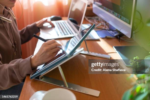 a young woman freelancer, designer or illustrator works remotely from home at a computer, draws on a graphics tablet. - ilustrador fotografías e imágenes de stock