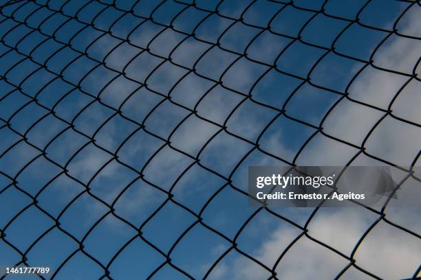 cloudy sky behind a fence - mesh fence stock pictures, royalty-free photos & images