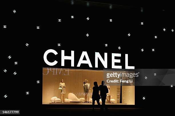 Chinese couple walk past the Chanel store on June 8, 2012 in Beijing, China. According to the World Luxury Association 2011 annual official report ,...
