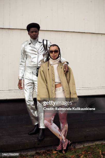 Alphons Amuri wearing a grey turtle neck, silver pants, and silver jacket, and Fia Hamelijnck wearing a knitted crop top, matching knitted white mini...