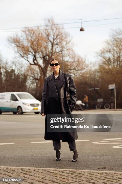 Darja Barannik wearing black sunglasses, a white t-shirt, a dark gray buttoned neck wool polo shirt, a gold large chain pendant necklace, a black...