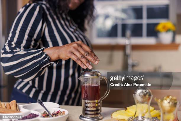 le mani della donna afroamericana nera: preparare la tisana usando una pressa francese nella sua cucina. - "alex potemkin" or "krakozawr" foto e immagini stock