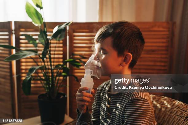 poor boy have a problem with chest coughing holding inhaler mask, child using the volumtic for breathing treatment, kid having asthma allergy using the asthma inhaler, healthcare and medicine concept - nebulizador fotografías e imágenes de stock