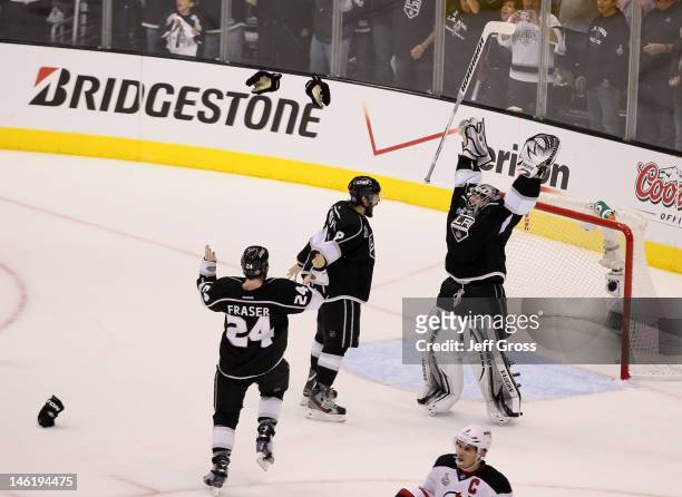 Drew Doughty, Jonathan Quick and Colin Fraser of the Los Angeles Kings celebrate the Kings 6-1 victory as Zach Parise of the New Jersey Devils looks...