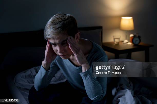 depressed senior asian woman sitting in bed cannot sleep from insomnia - slaappil stockfoto's en -beelden