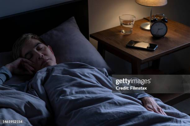 depressed senior woman lying in bed cannot sleep from insomnia - woman sleeping stock pictures, royalty-free photos & images