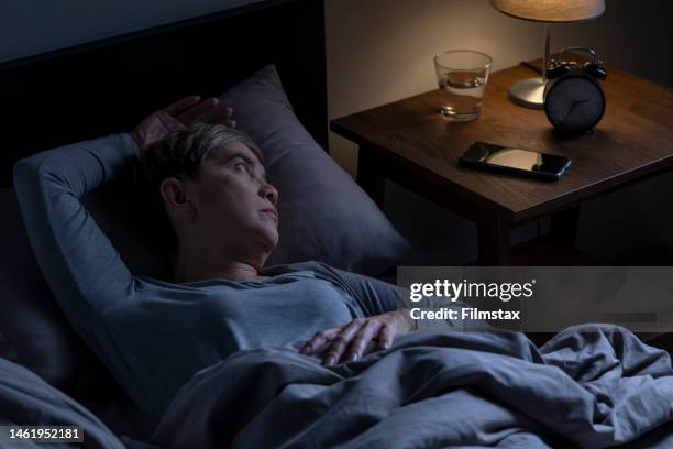 depressed senior woman lying in bed cannot sleep from insomnia - insomnia stock pictures, royalty-free photos & images
