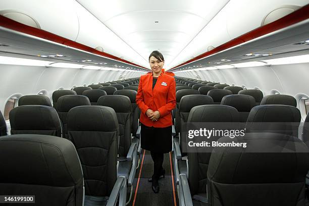 Jetstar Japan Co. Cabin attendant poses as she stands in the economy class cabin of the company's Airbus SAS A320 aircraft during a media preview at...