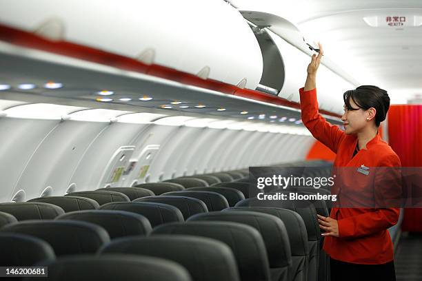 Jetstar Japan Co. Flight attendant opens an overhead storage bin in the economy class cabin of the company's Airbus SAS A320 aircraft during a media...