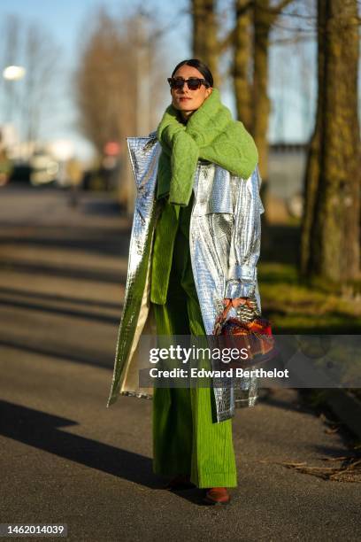 Julia Haghjoo wears brown print pattern sunglasses, a green embroidered wool pullover knot at the shoulder, a green ribbed velvet blazer jacket,...